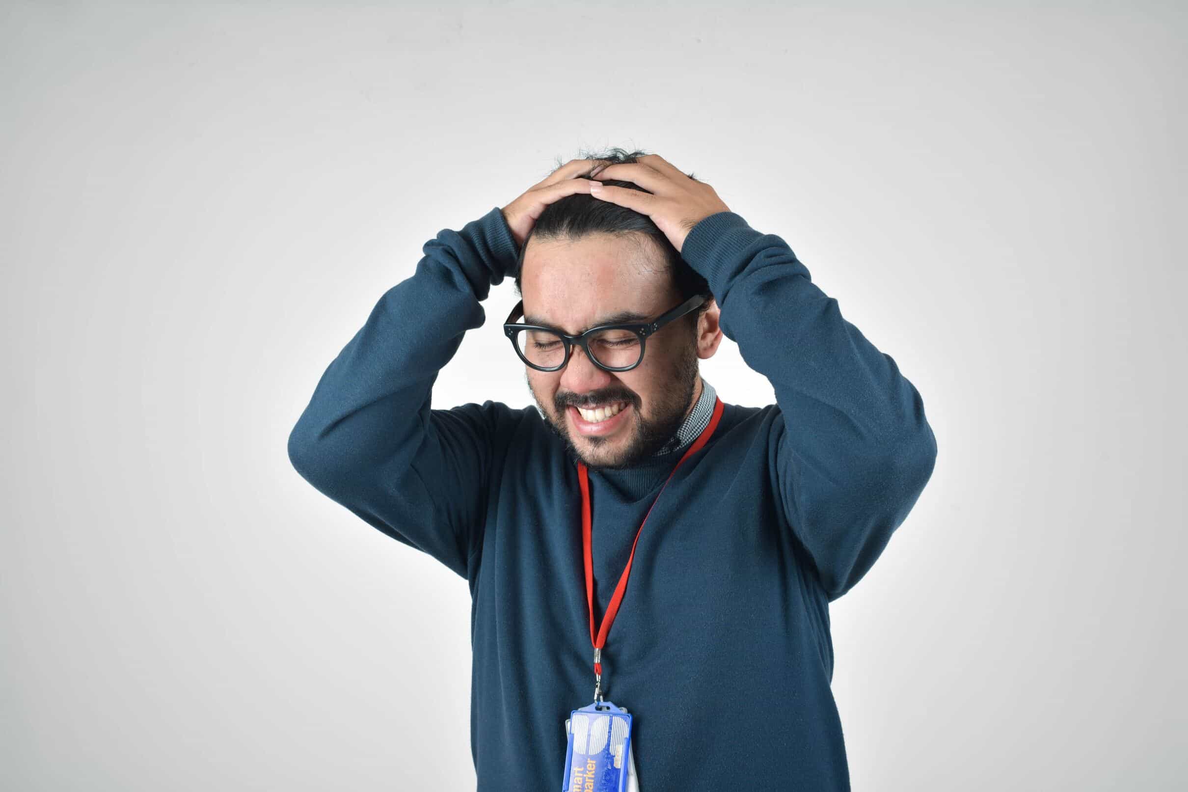 A man sitting at a desk, holding his head in his hands, visibly stressed and overwhelmed while reviewing car finance documents.