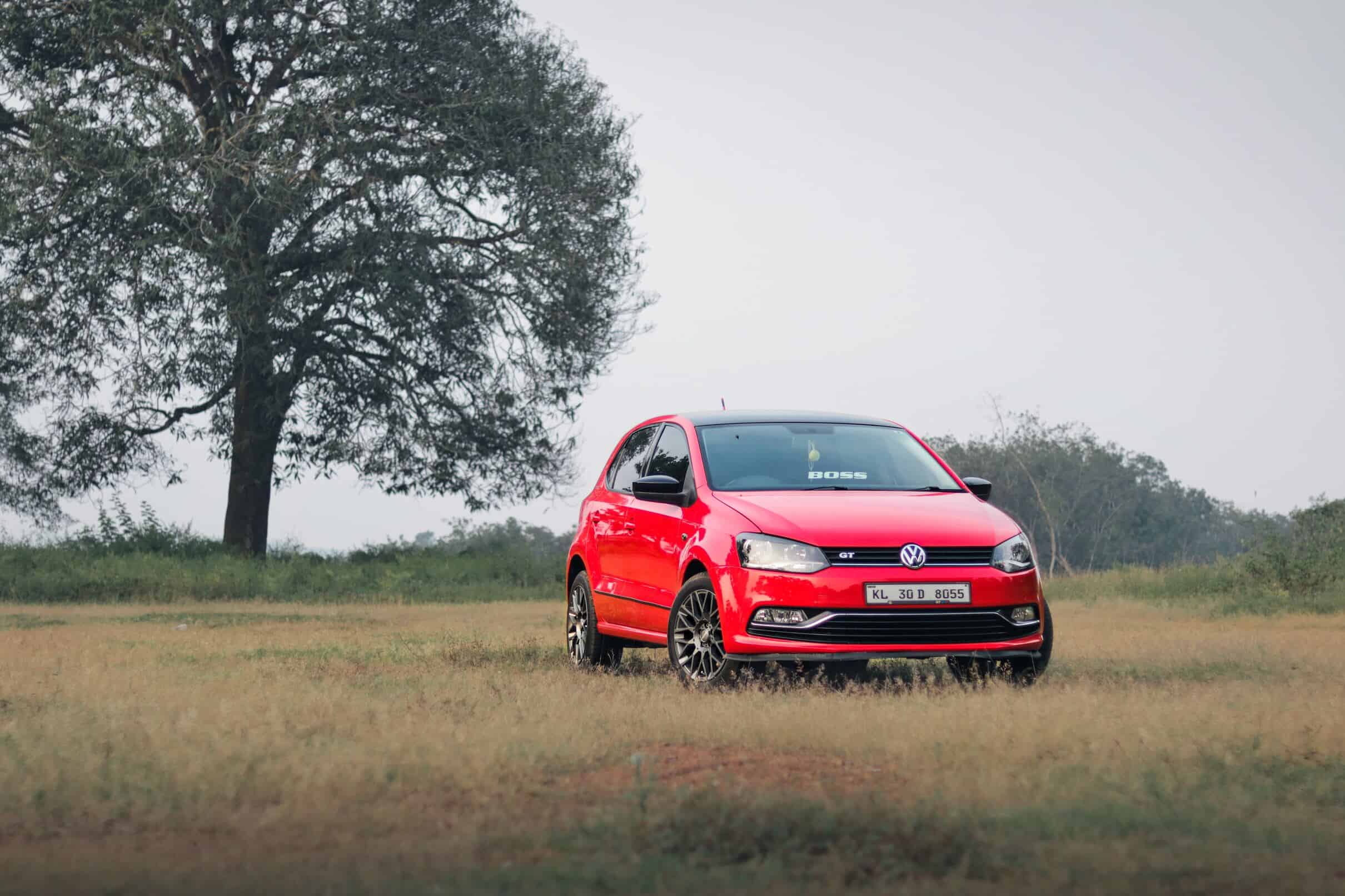 Red Volkswagen Polo parked in an urban setting, showcasing its modern design and vibrant character.