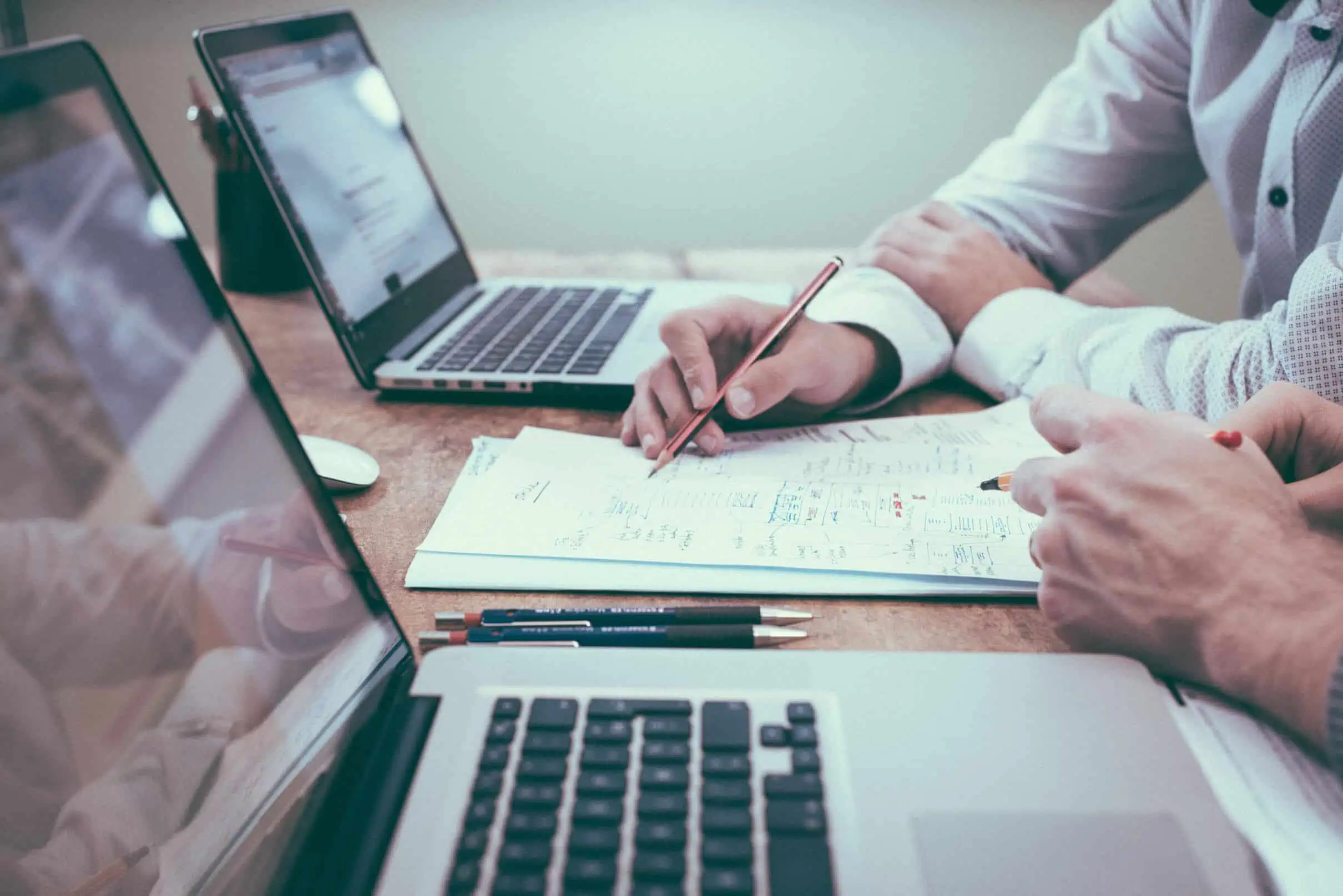 Financial planning and cost considerations concept: A calculator, coins, and documents on a desk.