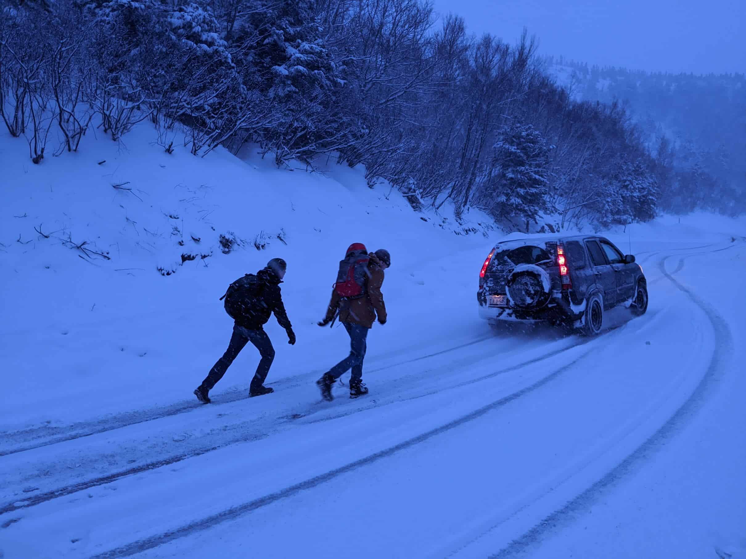 Group of people walking in a snowstorm after car breakdown